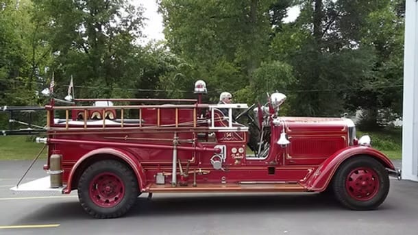The Speigletown District Volunteer Fire Company's beautifully preserved 1936 American LaFrance fire truck, in red with gold lettering, parked outside.