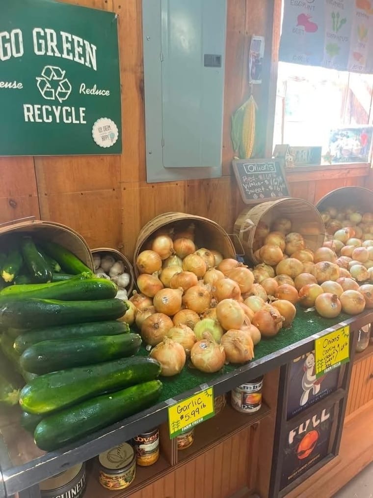 Bushel baskets of onions, garlic, and fresh zucchini on display at the farm stand.